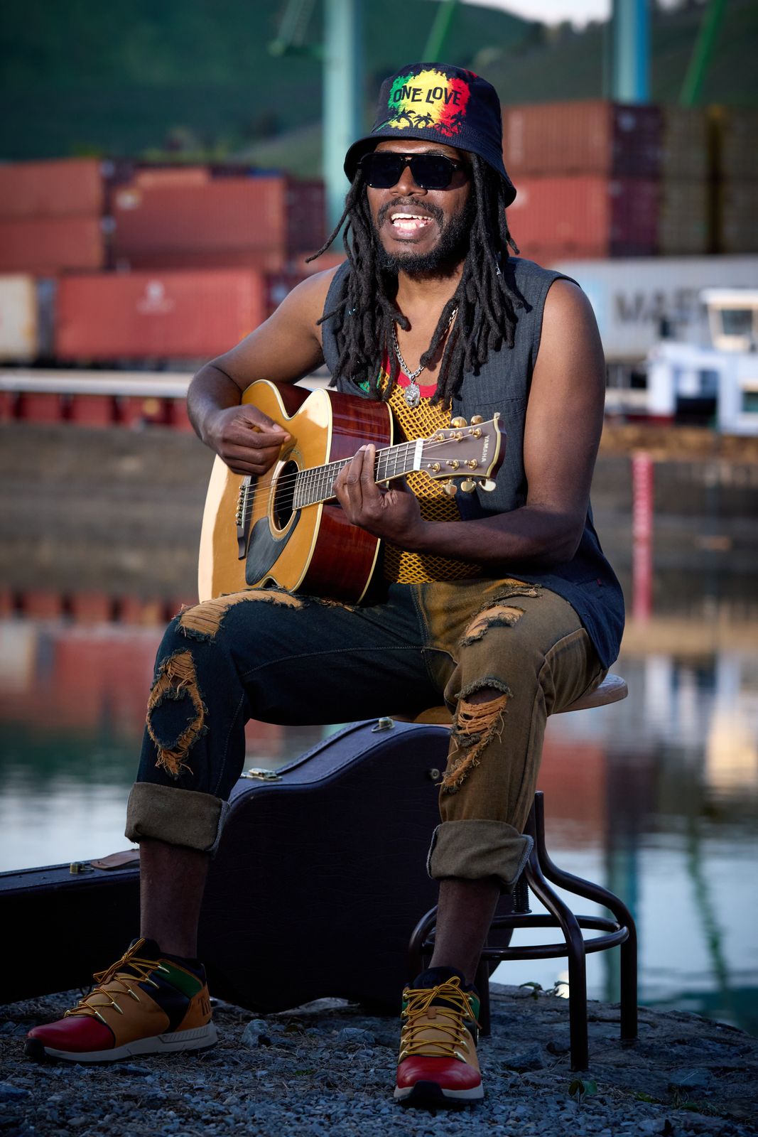 Anthony Locks seated with an acoustic guitar at a container terminal