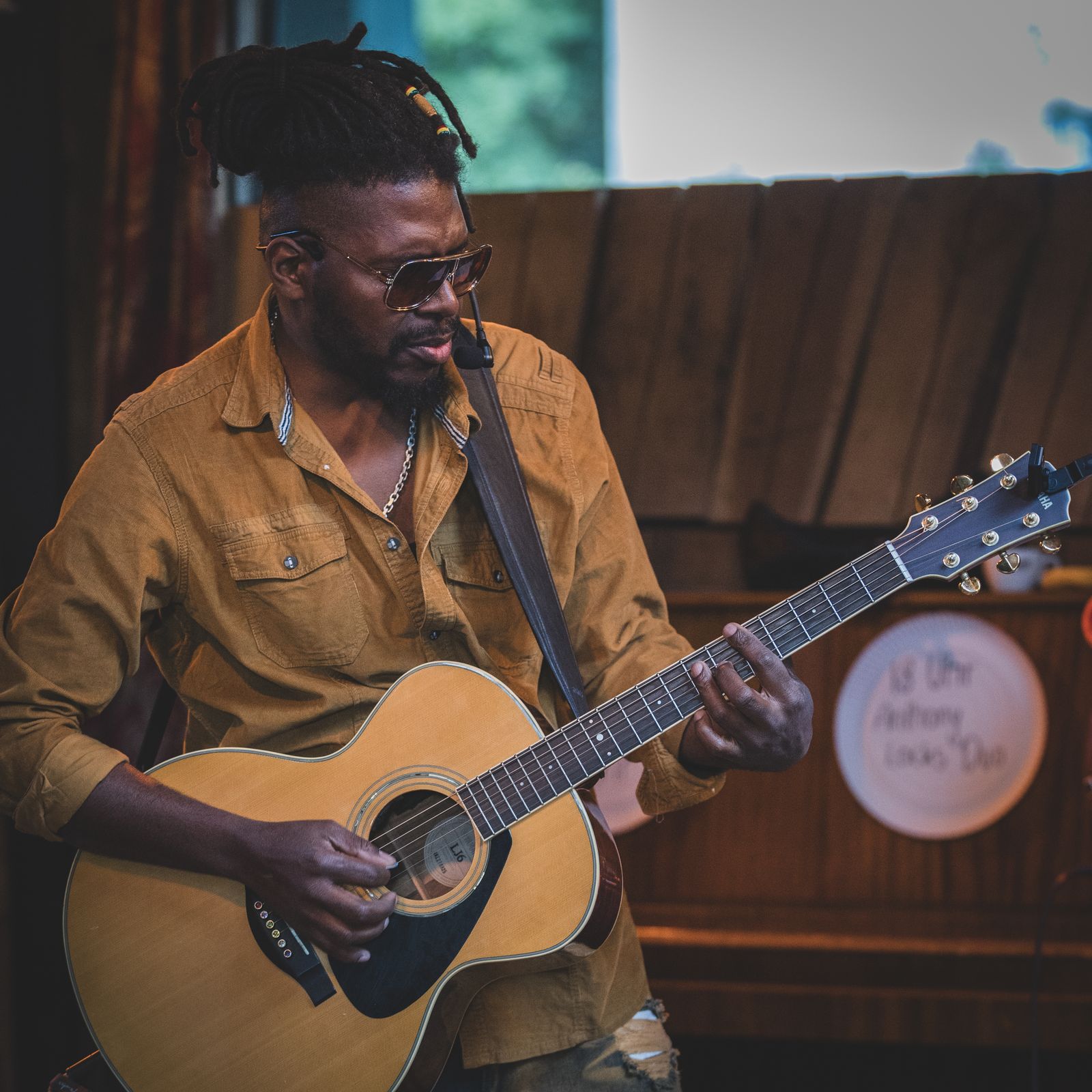 Anthony Locks playing acoustic guitar live on stage in a venue