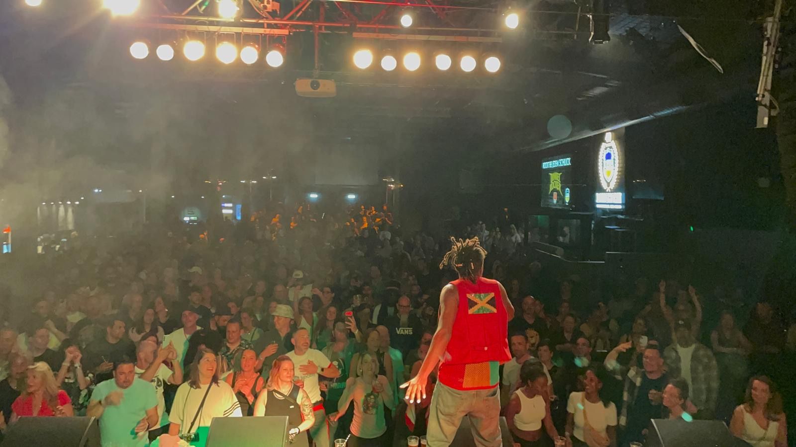 View from the stage behind Anthony Locks over a full hall, hands in the air