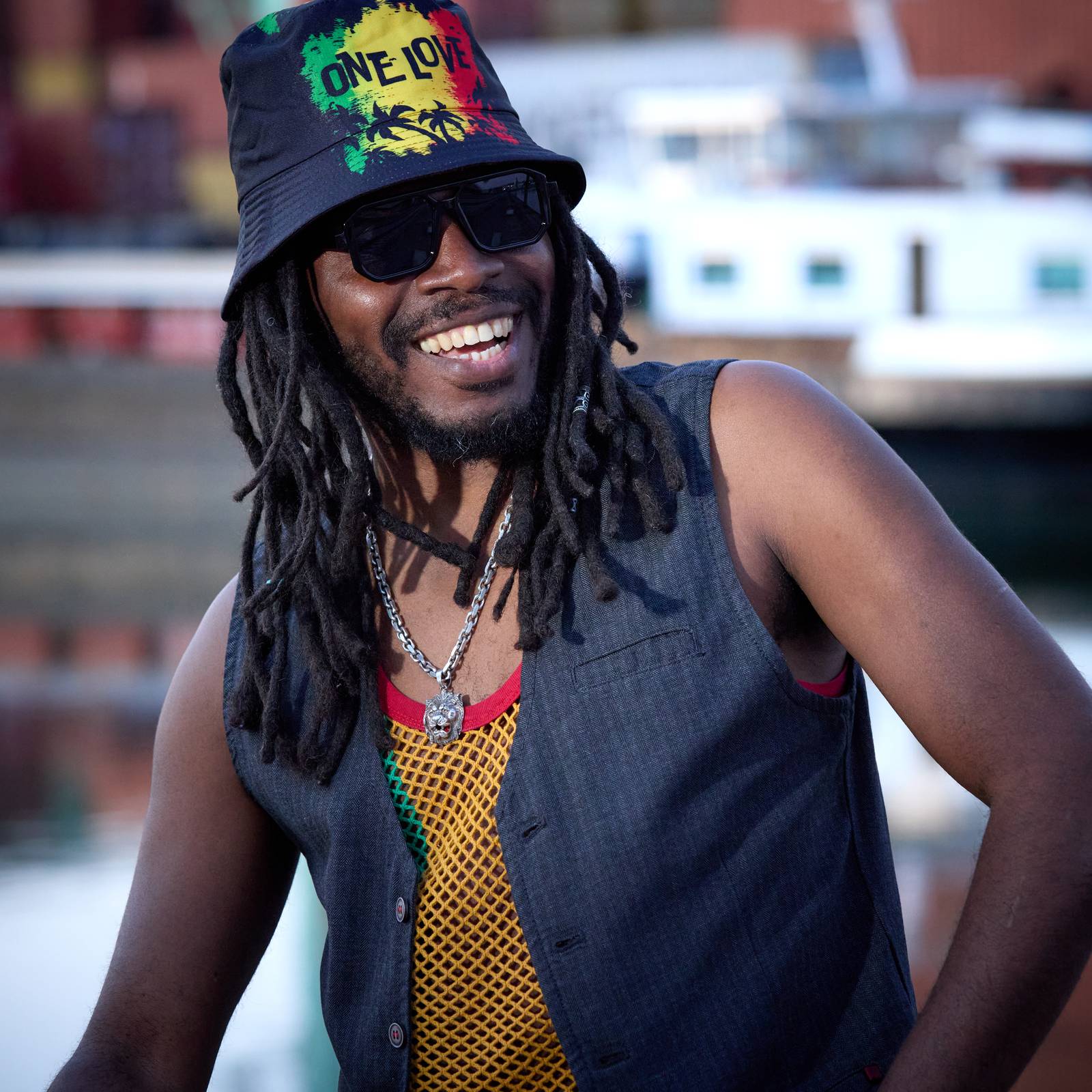 Press portrait of Anthony Locks, smiling, in a bucket hat at the harbour